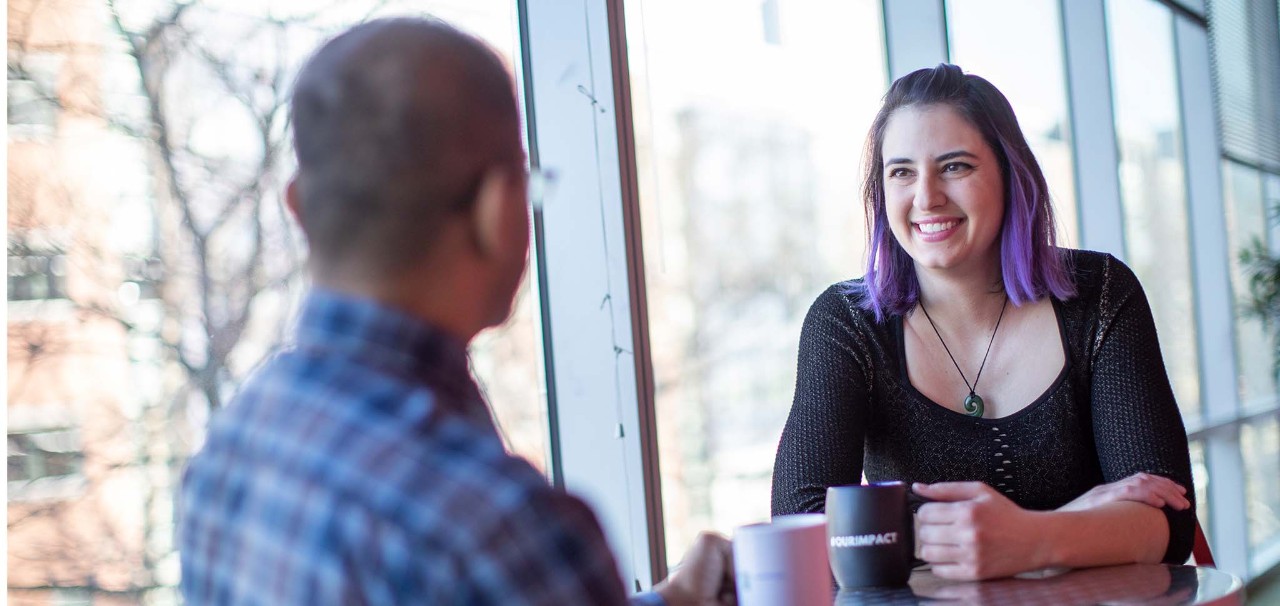 Foto van twee medewerkers die een gesprek voeren
